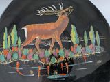a decorative plate with a deer on it on a table