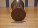 a penny sitting on a wooden table next to a cup