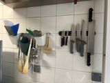 many knives and spoons hanging on the wall in the kitchen