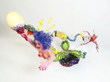 des figurines aux couleurs vives représentant une femme et un insecte sur fond blanc