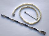 un collier blanc avec un fermoir en argent et un collier de perles blanches