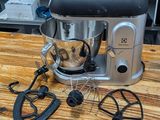 a silver mixer on a wooden table in a kitchen