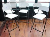 quatre chaises pliantes blanches posées devant une fenêtre, sur un parquet en bois massif