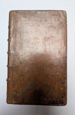 un vieux livre posé sur une table à côté d'un mur blanc