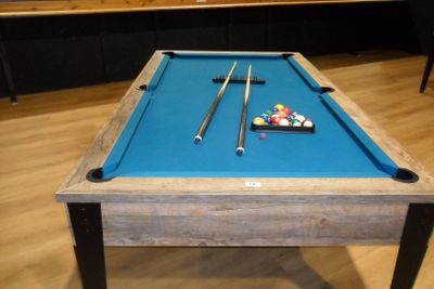 une table de billard recouverte d'un drap bleu, dans une pièce
