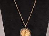 a necklace with a gold coin on a black mannequin