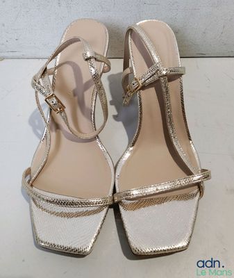 gold and white high heeled sandals on a white surface