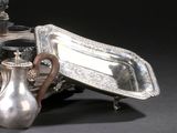 un plateau en argent et une théière en argent posés sur une table