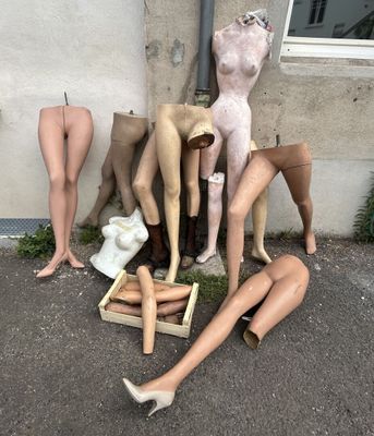 de nombreux mannequins assis par terre devant un immeuble