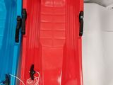 two red and blue plastic sleds on a white sheet