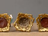 three pieces of gold and red stone are sitting on a table