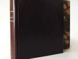 an old book with a brown cover sitting on top of a white table