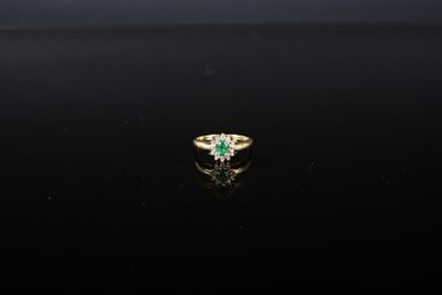 une bague en émeraude et diamant sur une surface noire