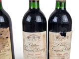 three bottles of red wine sit next to each other on a white surface