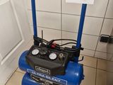 a blue air compressor sitting on the floor in the bathroom