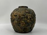 un petit vase posé sur une surface blanche