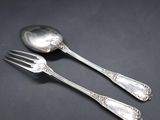 two silver spoons and a fork on a black surface