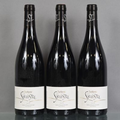 Trois bouteilles de vin sont alignées sur une table en verre