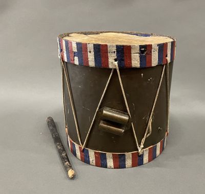 un petit tambour avec un bâton en bois posé devant