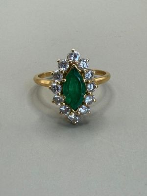 a close up of a green and white diamond ring on a table