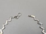 a close up of a silver necklace on a gray surface