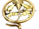 une image représentant une broche en or ornée de feuilles et d'une perle