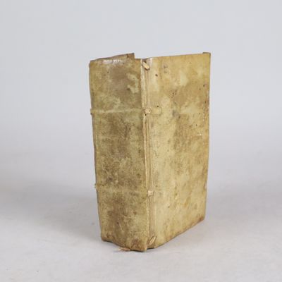 un vieux livre posé sur une table à côté d'un mur blanc