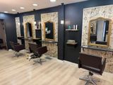 a photo of a hair salon with chairs and mirrors