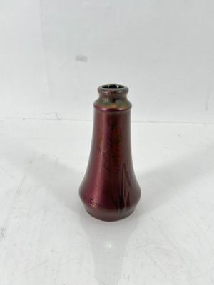un vase rouge posé sur une surface blanche