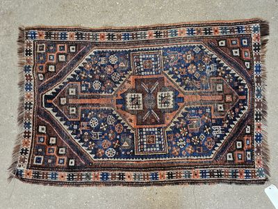 Petit tapis en laine à motifs géométriques sur fond brun.
