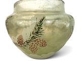 a glass vase with pine cones on it on a white background