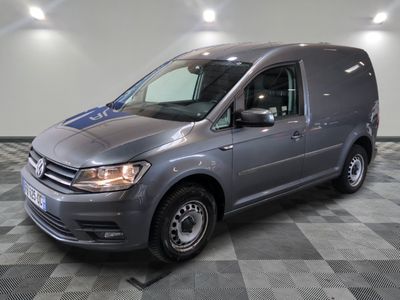La camionnette grise est garée dans le garage, sur un sol à damier.