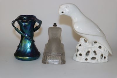 un oiseau blanc perché sur un vase, à côté de deux autres figurines