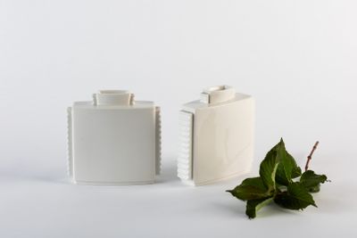 deux vases blancs posés l'un à côté de l'autre sur une surface blanche