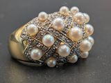une bague ornée de perles et de diamants, posée sur une table