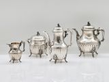 three silver teapots and a coffee pot on a white surface
