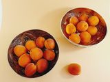two bowls of apricots on a table next to a bowl of apricots