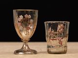two glasses sitting on a table with a black background