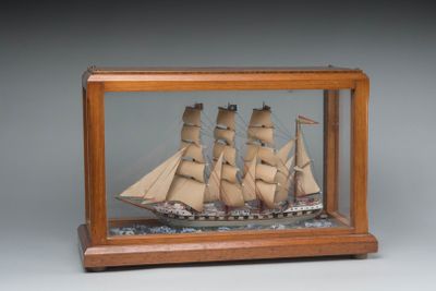 une petite maquette de bateau en bois exposée dans une vitrine