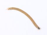 a close up of a gold bracelet on a white surface