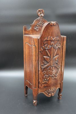 a small wooden cabinet with a carved design on the front