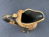 a black vase with a wooden handle on a blue background