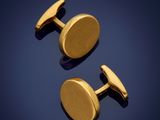a pair of gold cufflinks on a blue background
