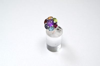 silver ring with multi colored stones on top of a white surface