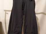 a pair of black pants hanging on a hanger in front of a white wall