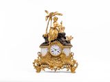 une horloge en or surmontée d'une statue
