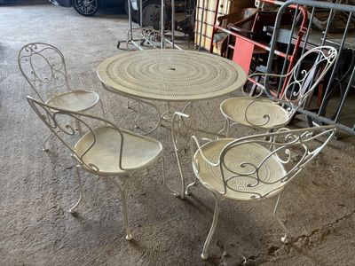 quatre chaises et une table posées à même le sol dans un garage