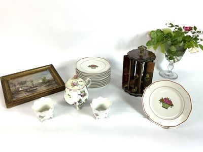 a table with a vase of flowers, plates, and a vase of flowers