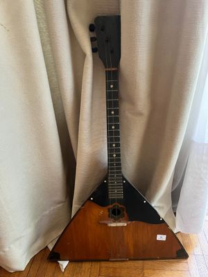 une guitare posée sur un support devant un rideau
