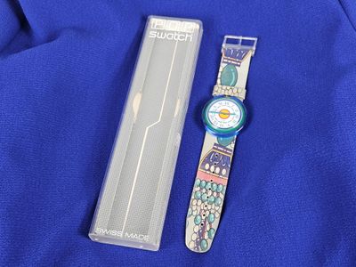 a close up of a watch on a blue cloth next to a box